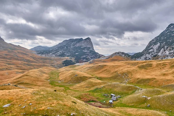 Rotsachtige bergen bedekt met herfstweide tegen de achtergrond van een stormachtige hemel — Stockfoto