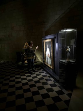 Fontevraud, France, Febuary 29, 2020 : Tourist watching a painting with a flashlight clipart