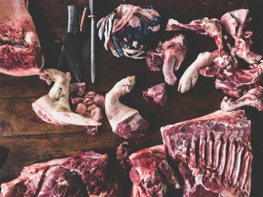 Kasabın karanlık ahşap çalışma masasında et ve bıçak var. Üst görünüm.