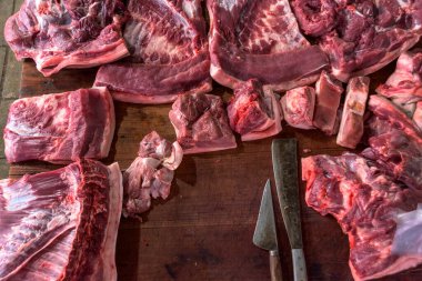 Kasabın karanlık ahşap çalışma masasında et ve bıçak var. Üst görünüm.