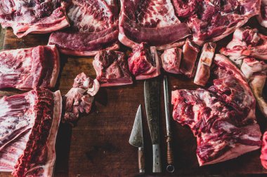 meat raw assortment and knife on the butcher's dark wooden working table. Top view. clipart