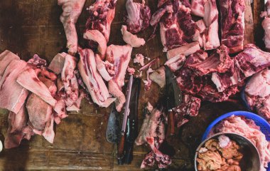 Kasabın karanlık ahşap çalışma masasında et ve bıçak var. Üst görünüm.