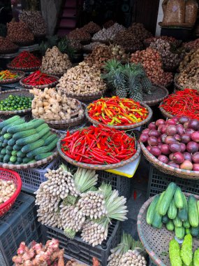 Hanoi, Vietnam, 30 Ocak 2020 - Sokakta satılık sebze ve meyvelerin bol olduğu bir sıranın ortasında bir satıcıyı görün. Kısa devre üretimi