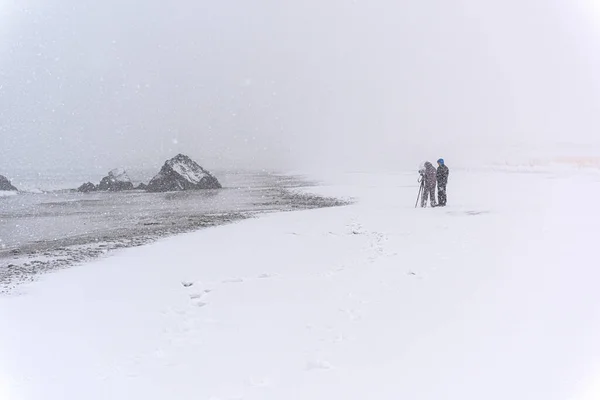 Tanımlanamayan Kişi Rüzgarlı Bir Kar Fırtınasında Sahilde Bir Kayanın Fotoğrafını — Stok fotoğraf