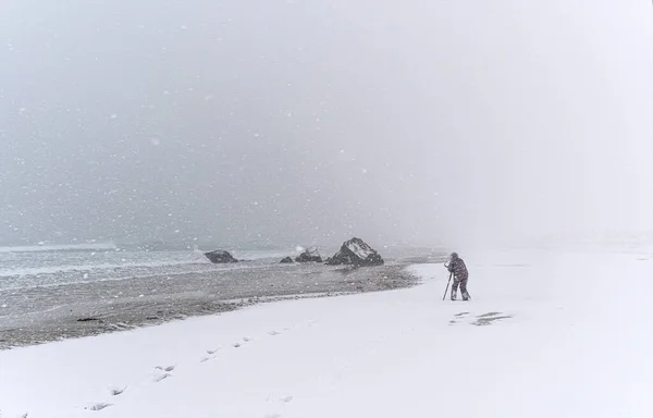 Tanımlanamayan Kişi Rüzgarlı Bir Kar Fırtınasında Sahilde Bir Kayanın Fotoğrafını — Stok fotoğraf