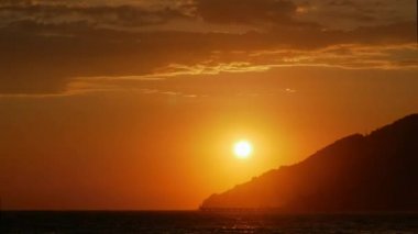 Timelapse. Güneş batımında dağın üzerinden gider. Deniz kıyıdan görüntülemek