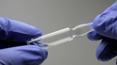 Mavi lateks eldiven bir erkekte ampul enjeksiyonlar için net bir çözüm ile tutar. Görünümü kapatın