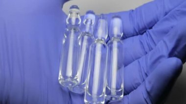 Mavi lateks eldiven bir erkekte ampul enjeksiyonlar için net bir çözüm ile tutar. Görünümü kapatın