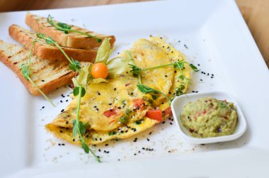İki yumurta sebzeli, domatesli, bezelyeli, soslu, fındıklı ve yeşillikli kahvaltı, beyaz tabakta çöplü tost.