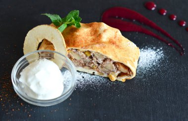 Elmalı tarçınlı turta ve böğürtlen soslu kuru üzüm ve siyah tabakta nane şekeri.