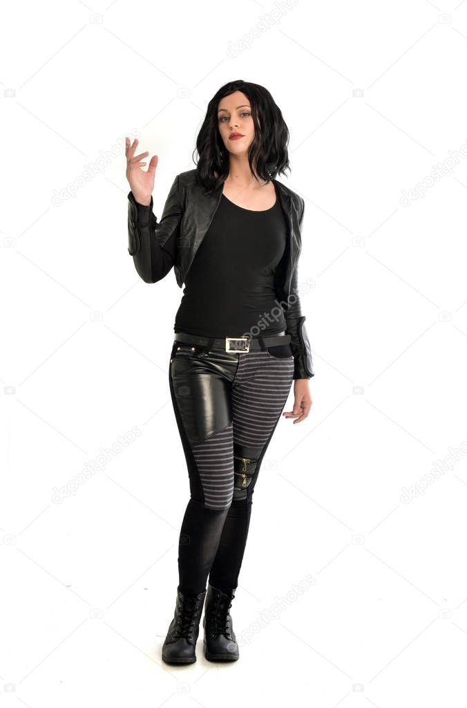 full length portrait of black haired girl wearing leather outfit. standing pose on a white background.
