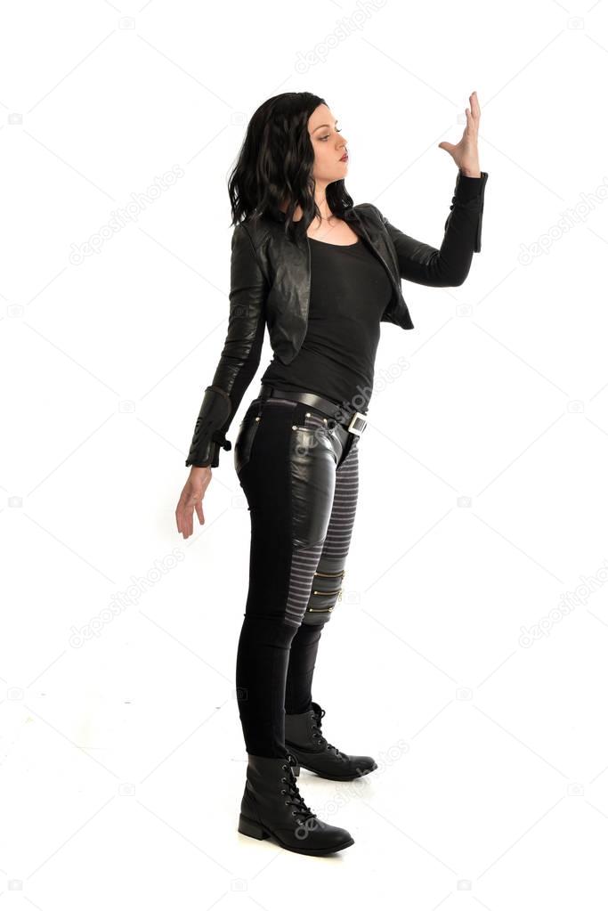 full length portrait of black haired girl wearing leather outfit. standing pose on a white background.