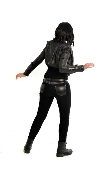 カメラから離れて直面している革の衣装を身に着けている黒い髪女の子の完全な長さの肖像画 ホワイト スタジオの背景に立ちポーズ — ストック写真