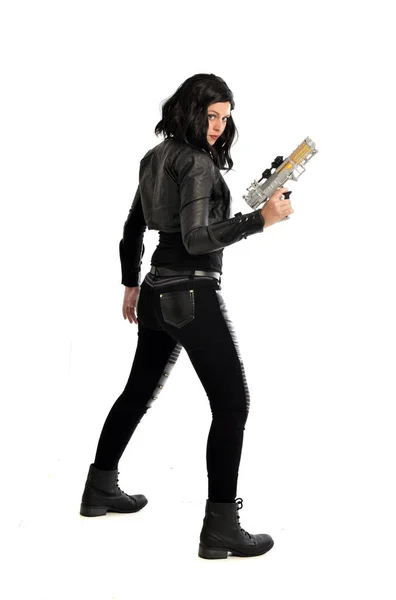 革の服を着て黒い髪の女の子の完全な長さの肖像画 ホワイト スタジオの背景に分離されて 銃を保持しながら立ちポーズ — ストック写真