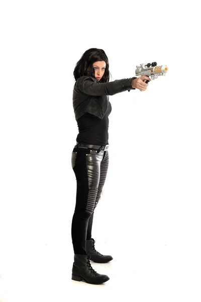全长黑色头发的女孩穿着皮革服装的肖像 手持枪站立姿势 在白色工作室背景下隔离 — 图库照片