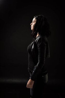 siyah arka plan üzerine aydınlatma moody deri elbiseler giymiş siyah saçlı kız portresi.