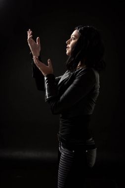 siyah arka plan üzerine aydınlatma moody deri elbiseler giymiş siyah saçlı kız portresi.