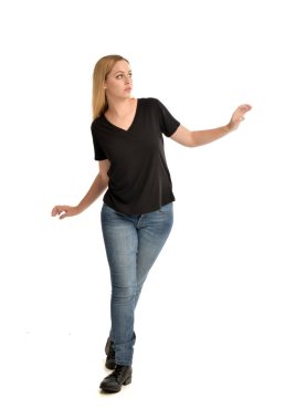 sarışın kız ayakta poz beyaz arka plan üzerinde temel siyah gömlek ve pantolon giyen tam uzunlukta portresi.