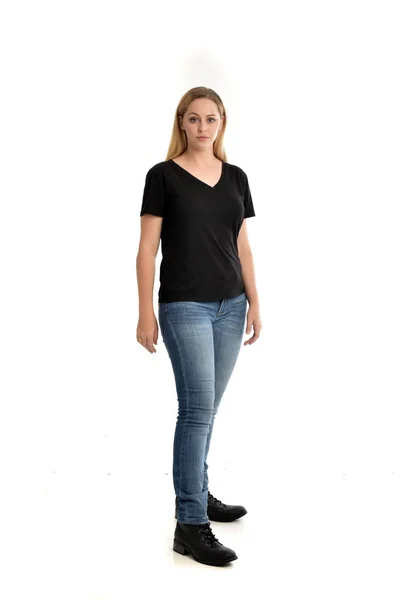 全长的肖像金发女郎身穿基本的黑色衬衫和牛仔裤 站立姿势在白色背景 — 图库照片