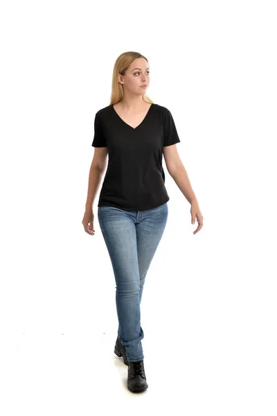 基本的な黒の シャツとジーンズを身に着けているブロンドの女の子は 白い背景の上の立ちポーズの完全な長さの肖像画 — ストック写真