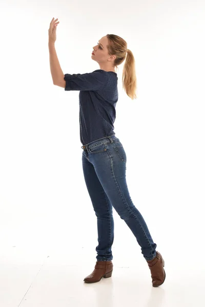 ホワイト スタジオの背景に Pose Isolated に立っているシンプルなブルーのシャツとジーンズを身に着けている女の子の完全な長さの肖像画 — ストック写真
