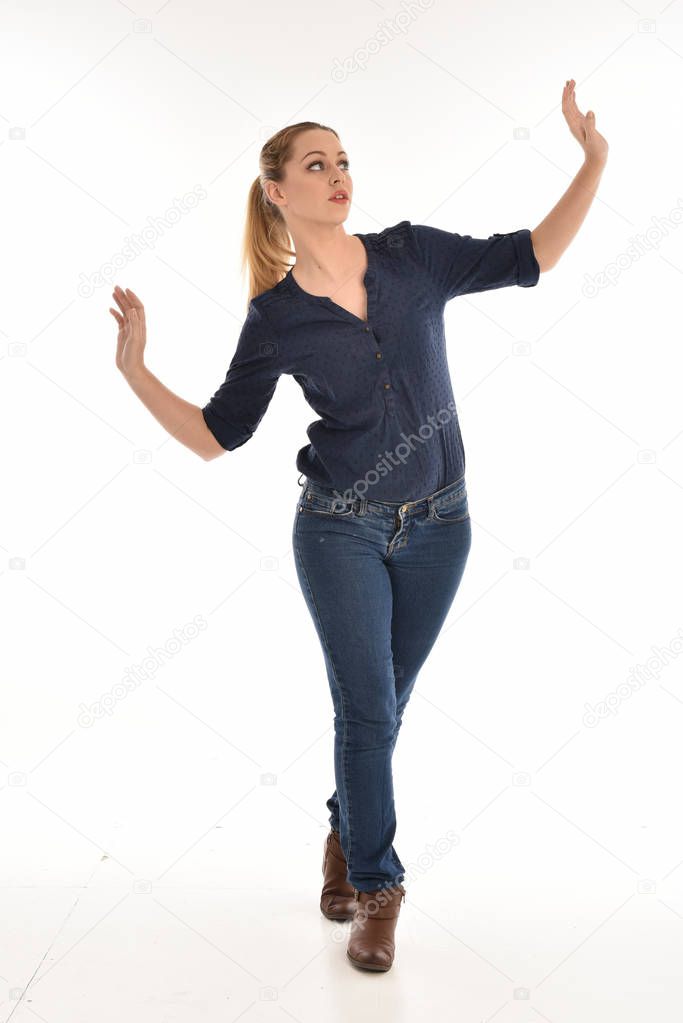 full length portrait of girl wearing simple blue shirt and jeans, standing pose.isolated on white studio background.