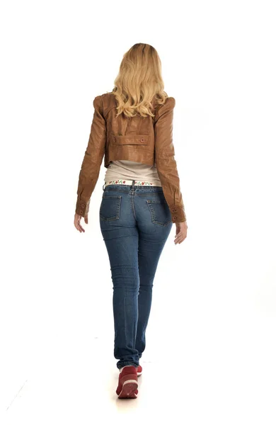 茶色のジャケットとジーンズを着ている金髪の女の子の完全な長さの肖像画 白い背景の上の立ちポーズ — ストック写真