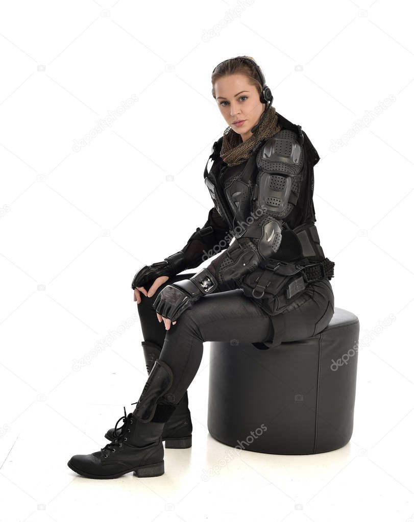 full length portrait of female wearing black  tactical armour, crouching pose, isolated on white studio background.