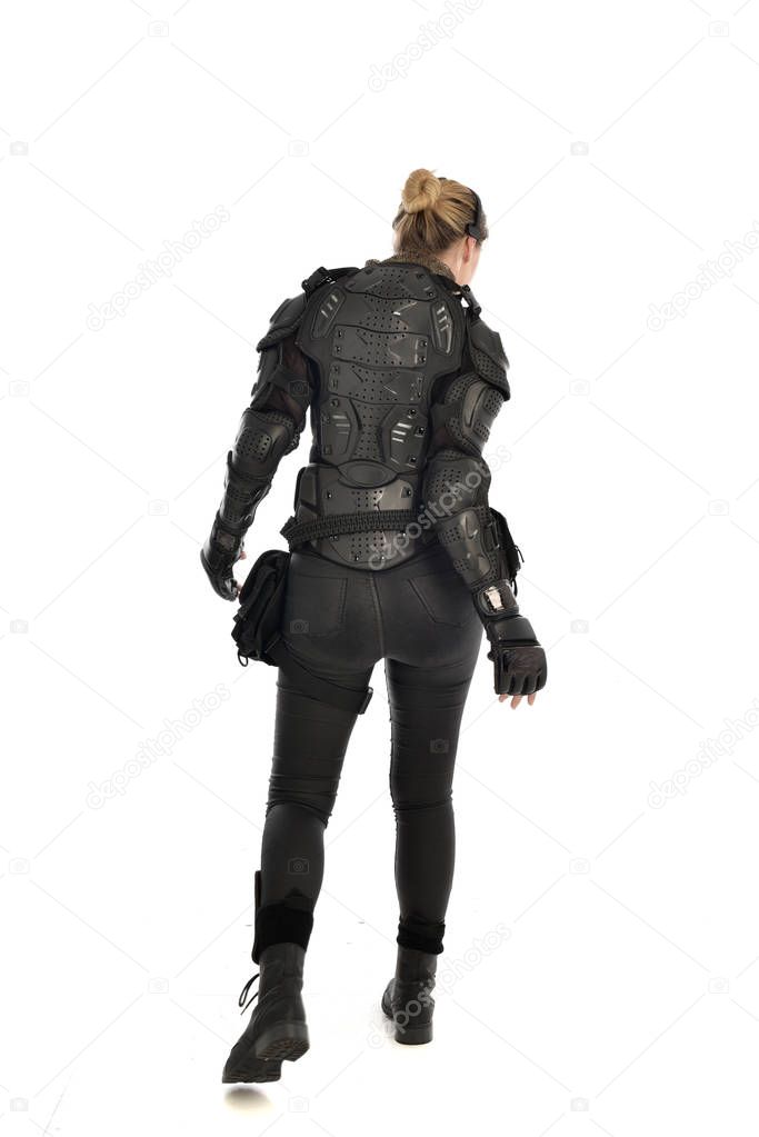 full length portrait of female  soldier wearing black  tactical armour  facing away from the camera, isolated on white studio background.