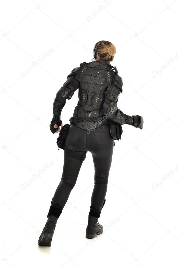full length portrait of female  soldier wearing black  tactical armour  facing away from the camera, isolated on white studio background.