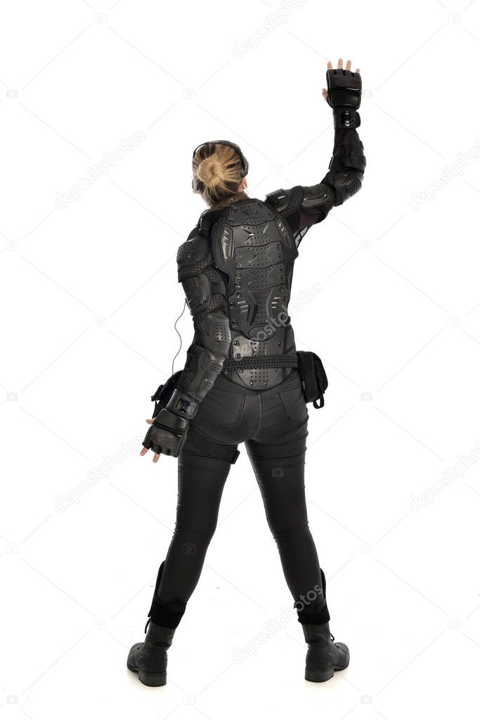 full length portrait of female  soldier wearing black  tactical armour  facing away from the camera, isolated on white studio background.