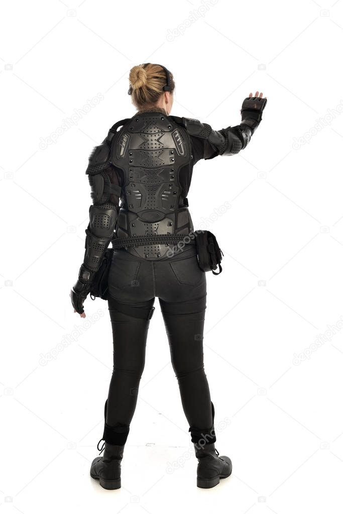 full length portrait of female  soldier wearing black  tactical armour  facing away from the camera, isolated on white studio background.