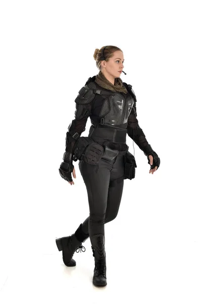 full length portrait of female  soldier wearing black  tactical armour, isolated on white studio background.