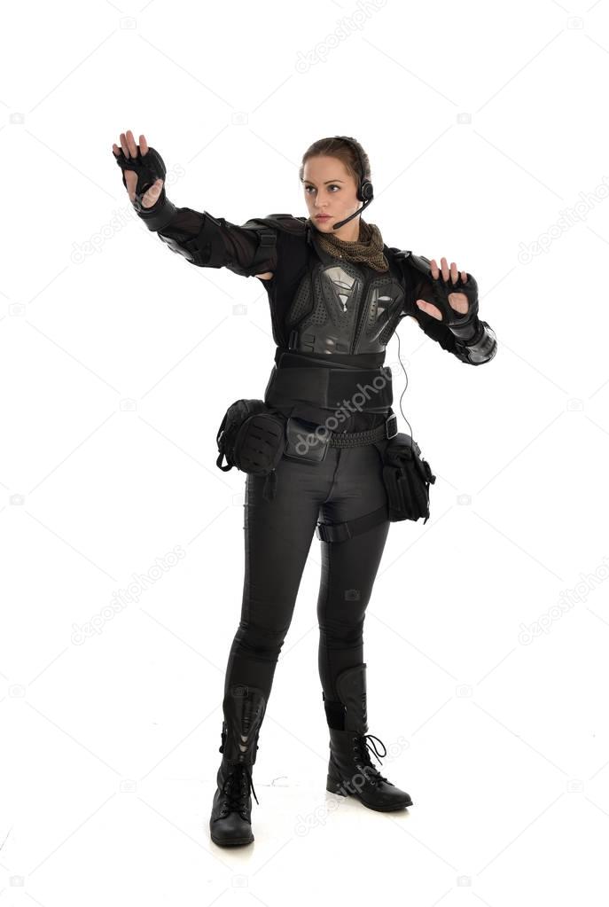 full length portrait of female  soldier wearing black  tactical armour, isolated on white studio background.