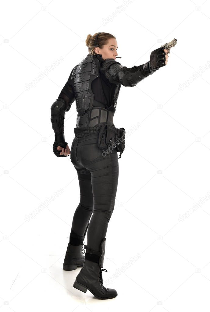full length portrait of female  soldier wearing black  tactical armour holding a gun, isolated on white studio background.