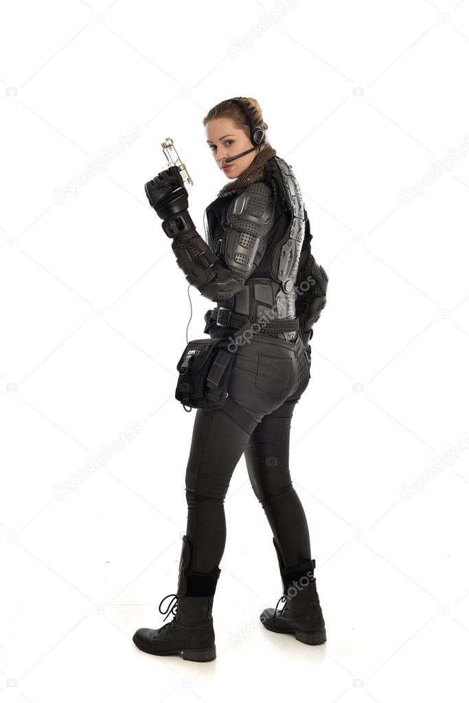 full length portrait of female  soldier wearing black  tactical armour holding a gun, isolated on white studio background.