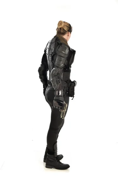 ホワイト スタジオの背景に分離された銃を保持して黒の戦術的なアーマーを着ていた女性の兵士の完全な長さの肖像画 — ストック写真