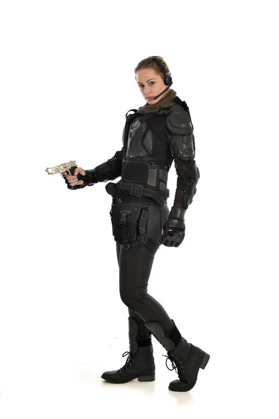 戦術的な黒の鎧を着て 白いスタジオ背景に分離された銃を保持している女性兵士の完全な長さの肖像画 — ストック写真