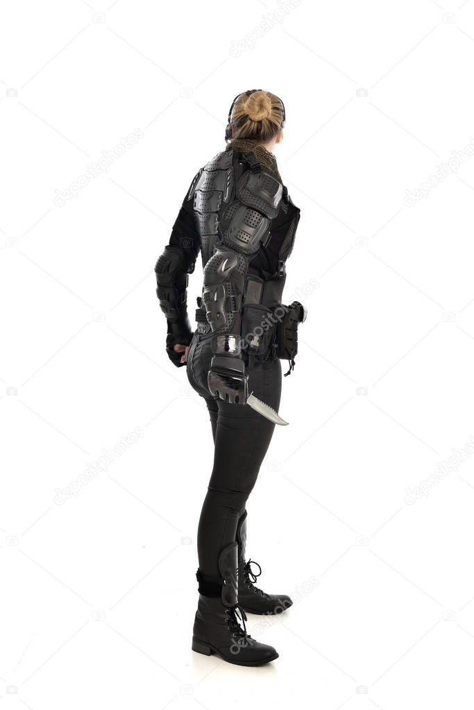 full length portrait of female  soldier wearing black  tactical armour, holding a knife, isolated on white studio background.