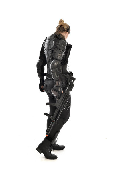 портрет женщины-солдата в чёрных тактических доспехах, держащей винтовку, изолированный на белом фоне студии
.