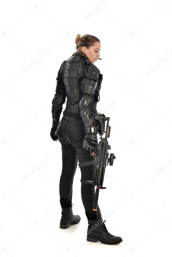 full length portrait of female  soldier wearing black  tactical armour, holding a rifle gun, isolated on white studio background.