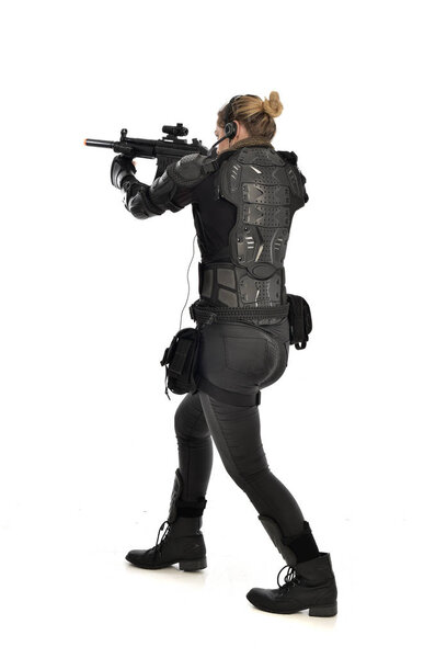 портрет женщины-солдата в чёрных тактических доспехах, держащей винтовку, изолированный на белом фоне студии
.