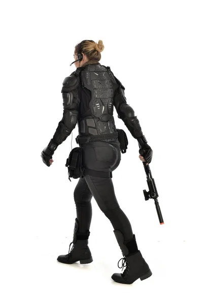 戦術的な黒の鎧を着て 白いスタジオ背景に分離されたライフル銃を保持している女性兵士の完全な長さの肖像画 — ストック写真