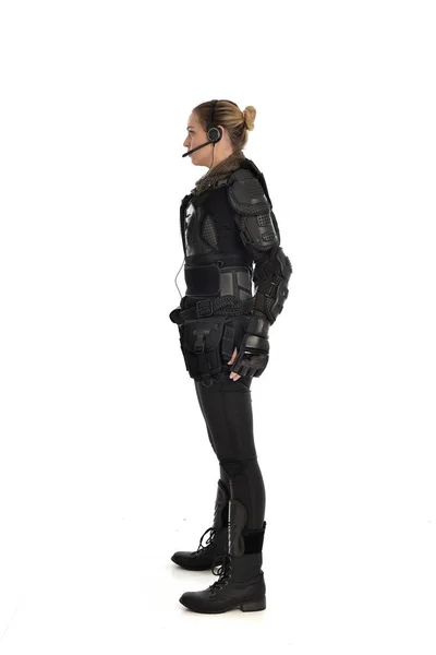 ホワイト スタジオの背景に分離されたプロファイルでは 立っている黒いの戦術的な武具を身に着けている女性の兵士の完全な長さの肖像画 — ストック写真