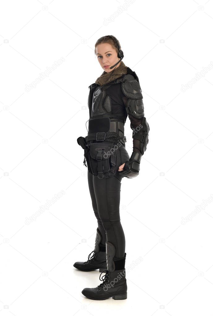 full length portrait of female  soldier wearing black  tactical armour, standing in profile, isolated on white studio background.