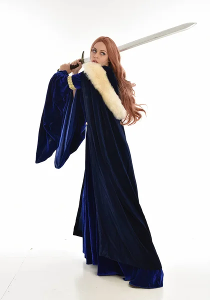 ブルー ベルベット中世のガウンと毛皮のマントを着た長い髪の女性の完全な長さの肖像画 カメラは 白い背景で隔離の背中立ちのポーズ — ストック写真