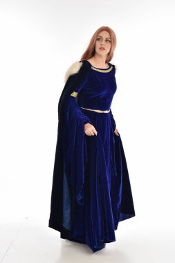 tam uzunlukta bir mavi kadife Ortaçağ elbisesi ve kürk Pelerin giyen kadın uzun saçlı portresi. ayakta poz, beyaz arka plan üzerinde izole.