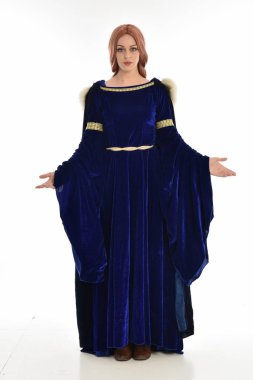 tam uzunlukta bir mavi kadife Ortaçağ elbisesi ve kürk Pelerin giyen kadın uzun saçlı portresi. ayakta poz, beyaz arka plan üzerinde izole.