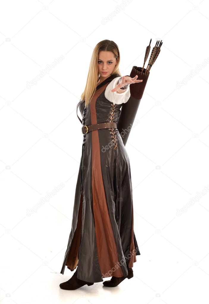 full length portrait of woman wearing brown medieval fantasy outfit, with a bow and arrow. standing pose on white studio background.