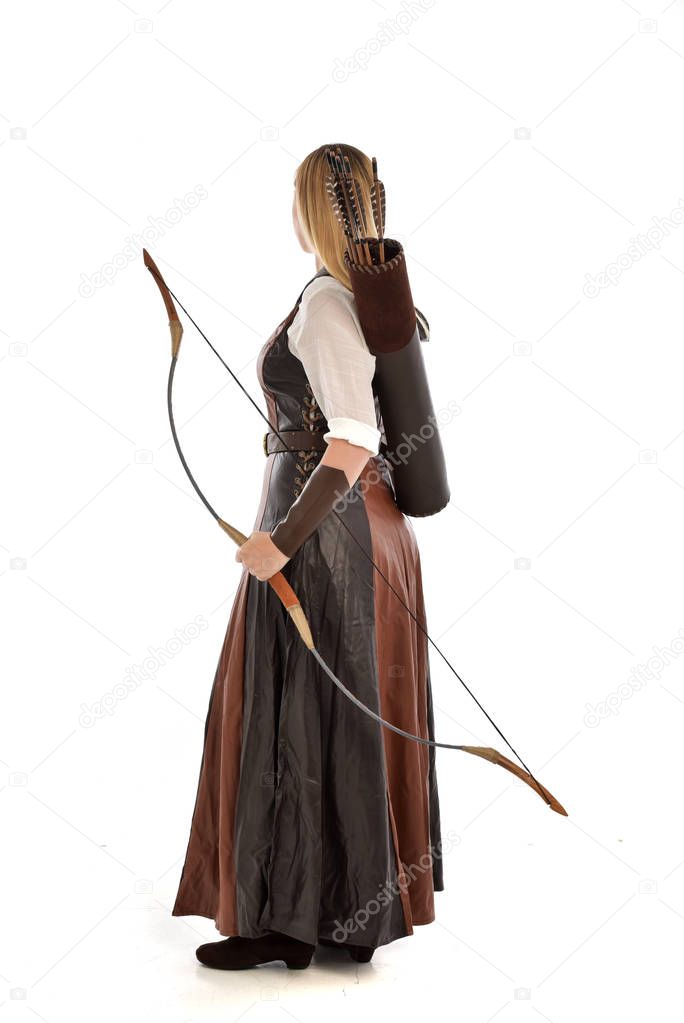 full length portrait of woman wearing brown medieval fantasy outfit, with a bow and arrow. standing pose on white studio background.